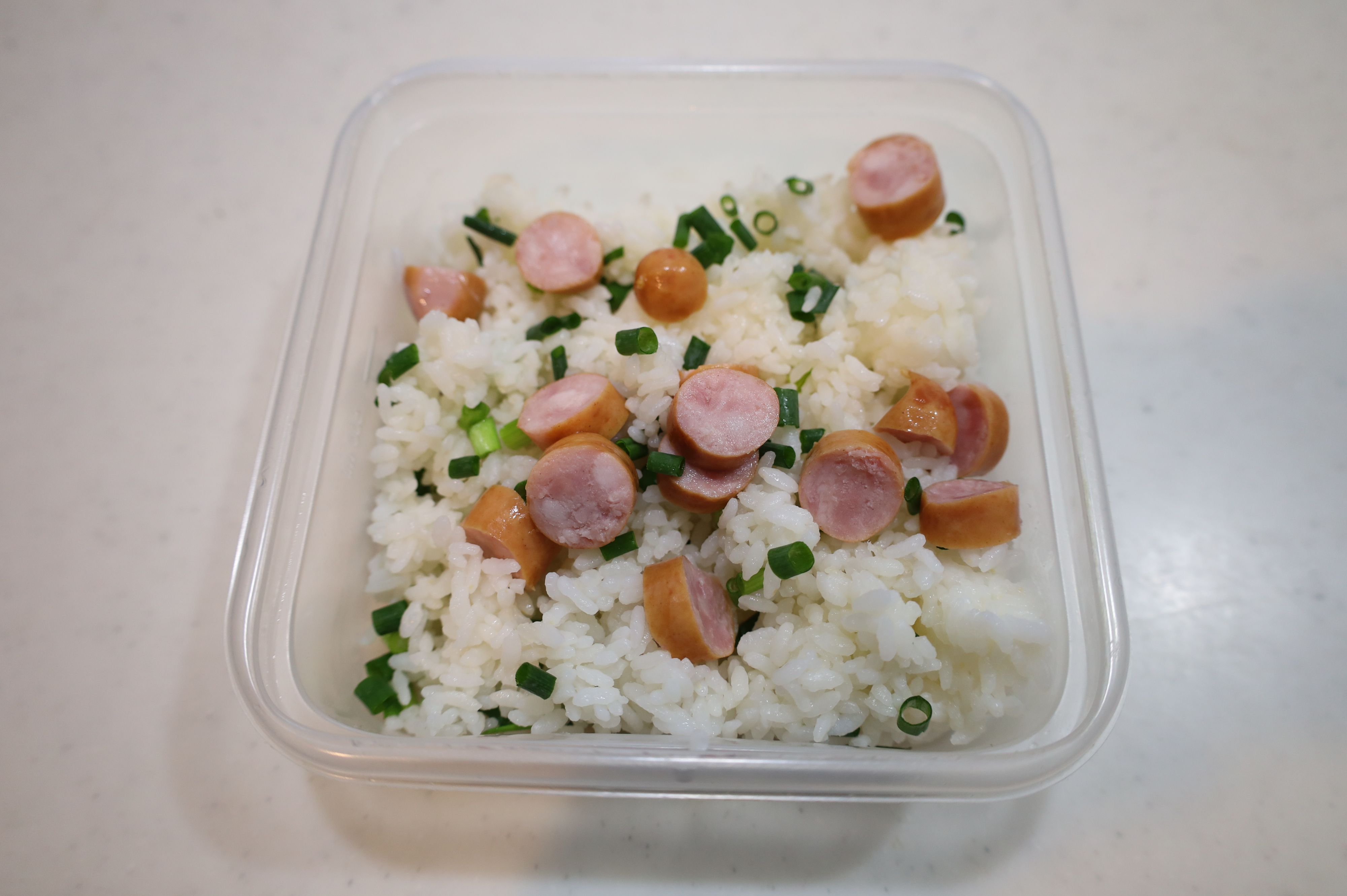 耐熱容器にご飯、ウインナー、青ねぎを入れる